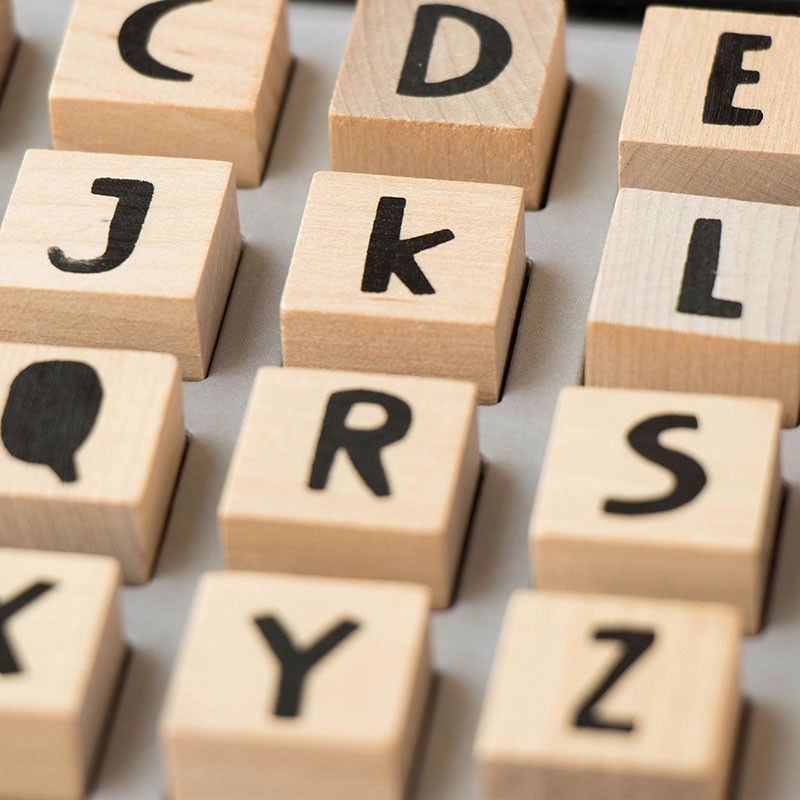 Holzwürfel mit schwarzen Buchstaben und Symbolen in verschiedenen Anordnungen, Detailaufnahme der Stempel