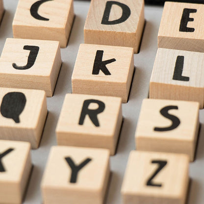 Holzwürfel mit schwarzen Buchstaben und Symbolen in verschiedenen Anordnungen, Detailaufnahme der Stempel