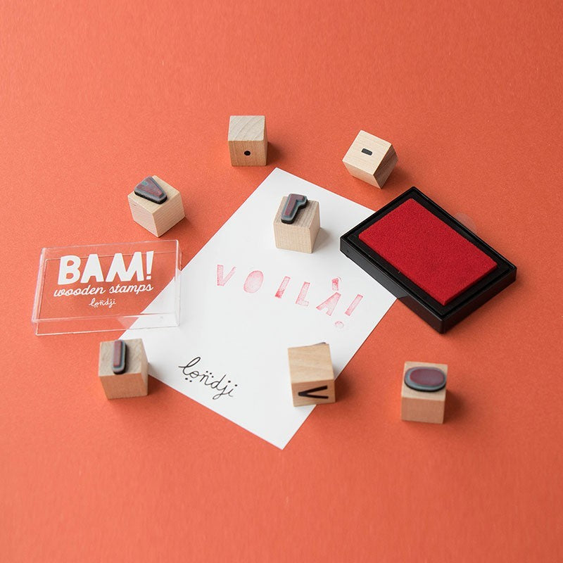 Londji BAM! Stempel-Set mit Holzwürfeln, rotem Kissen und gestempelten Wörtern auf weißem Papier