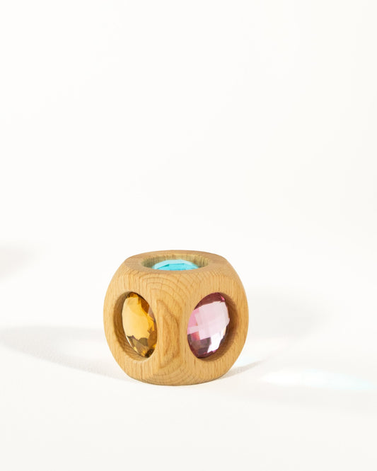 Bauspiel Zauberwürfel Pastell, Holzwürfel mit runden Aussparungen und farbigen Funkelsteinen in Rosa, Gelbgrün und Blau