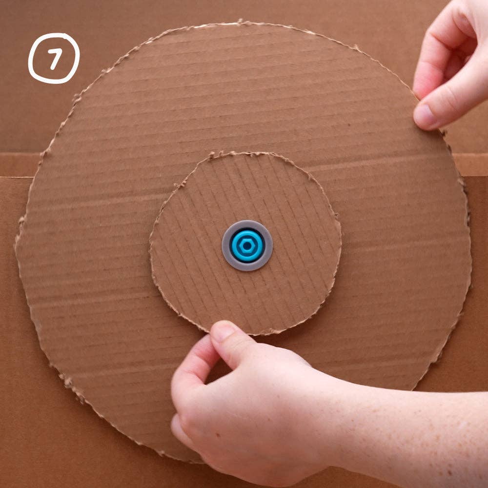 Hände drehen eine mit Makedo Roto-Ring befestigte Kartonscheibe, Schritt 7