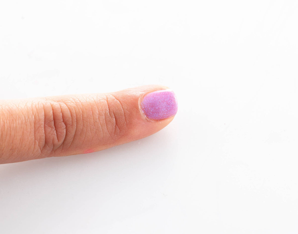 Namaki Nagellack abziehbar in Glitzerlila auf einem Fingernagel aufgetragen, Detailaufnahme