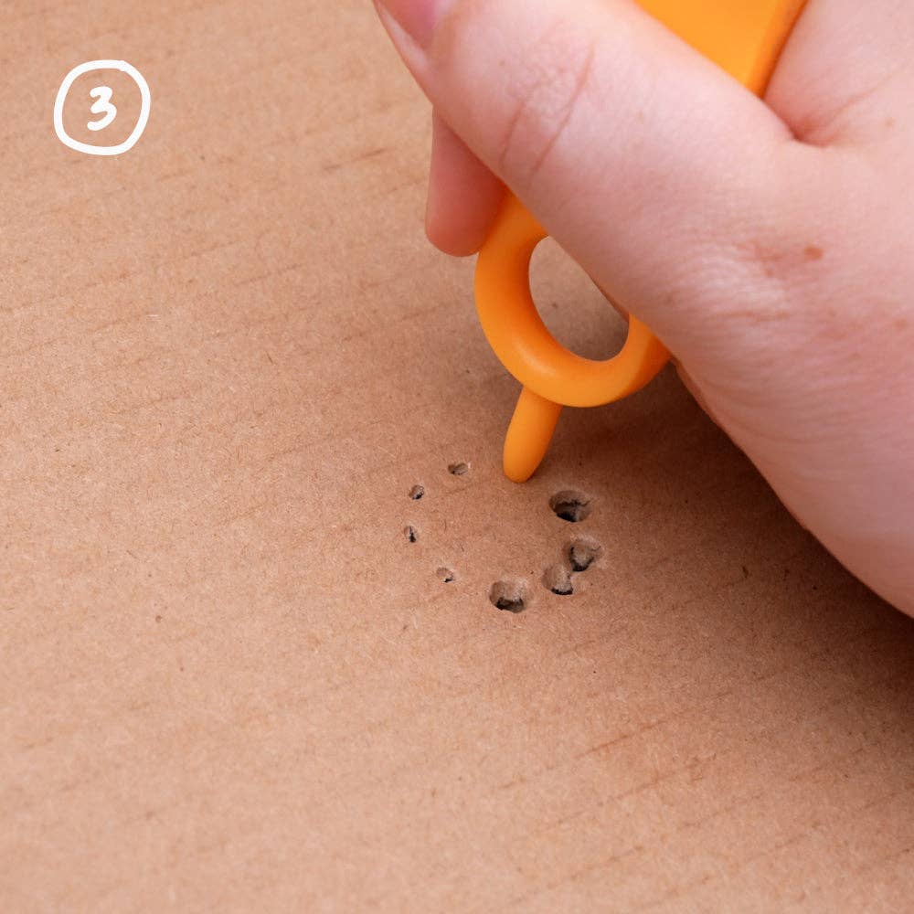 Kinderhand sticht mit dem orangen Makedo Mini-Tool kleine Löcher in Karton, Schritt 3