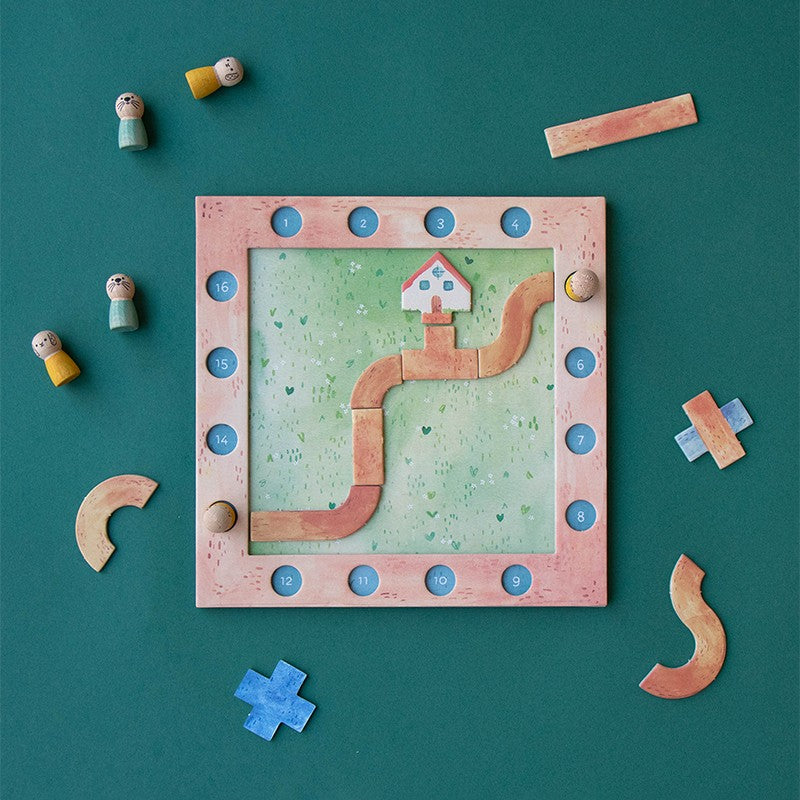 Londji Best Friends Spiel von oben mit rosa Brett, blauen Knöpfen, Holzfiguren und Puzzle-Teilen auf grünem Untergrund