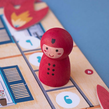 Rote Holzspielerfigur mit Gesicht und schwarzen Knöpfen auf dem Londji Save the Cat Spielplan