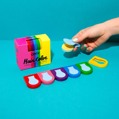 OMY Hair Color Haarkreide, bunte Farbstifte in Regenbogenfarben, Hand hält gelben Stift