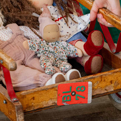 Käthe Kruse Waldorfpuppe NINI Blümchen sitzt mit anderen Puppen in einem alten Holzwagen
