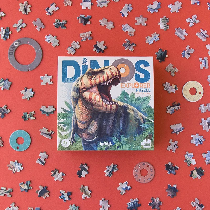 Londji Dino Explorer Puzzle, Verpackung mit Dinosaurier auf rotem Hintergrund, umgeben von Puzzleteilen