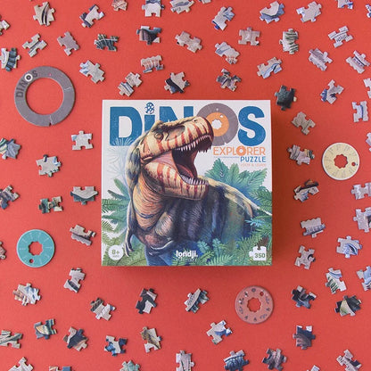 Londji Dino Explorer Puzzle, Verpackung mit Dinosaurier auf rotem Hintergrund, umgeben von Puzzleteilen