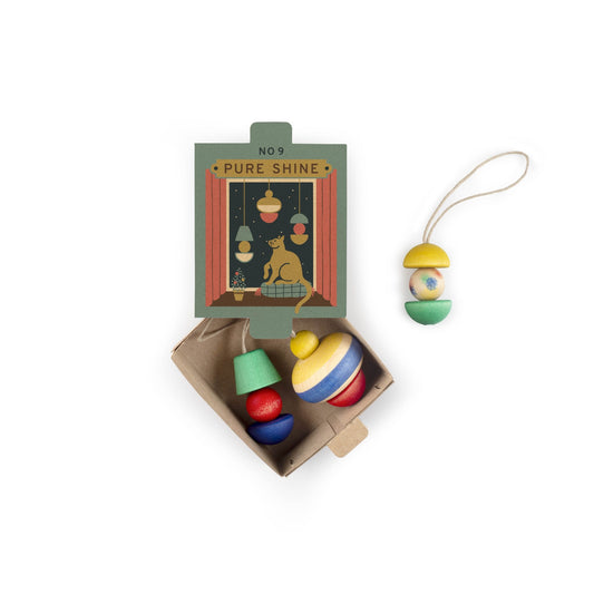 Grapat Ornaments Nº 9 Pure Shine: grüne Schachtel mit Motiv, bunte Holzanhänger im Karton und einer an einer Schnur daneben