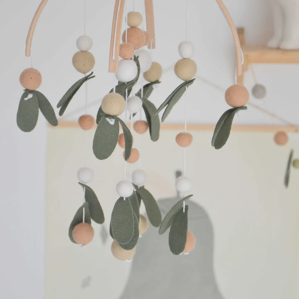 Blätter-Mobile von CALM for dreamers im Kinderzimmer, Filzkugeln und -blätter an zwei Holzbögen