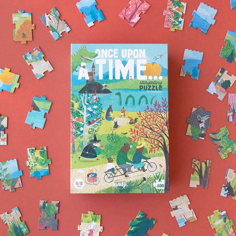 Londji Puzzle Once Upon a Time, Schachteln-Verpackung auf rotem Grund umgeben von bunten Puzzleteilen