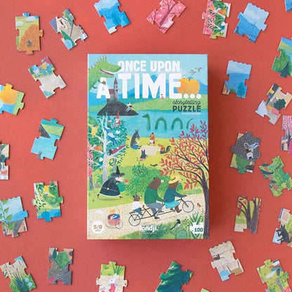 Londji Puzzle Once Upon a Time, Schachteln-Verpackung auf rotem Grund umgeben von bunten Puzzleteilen