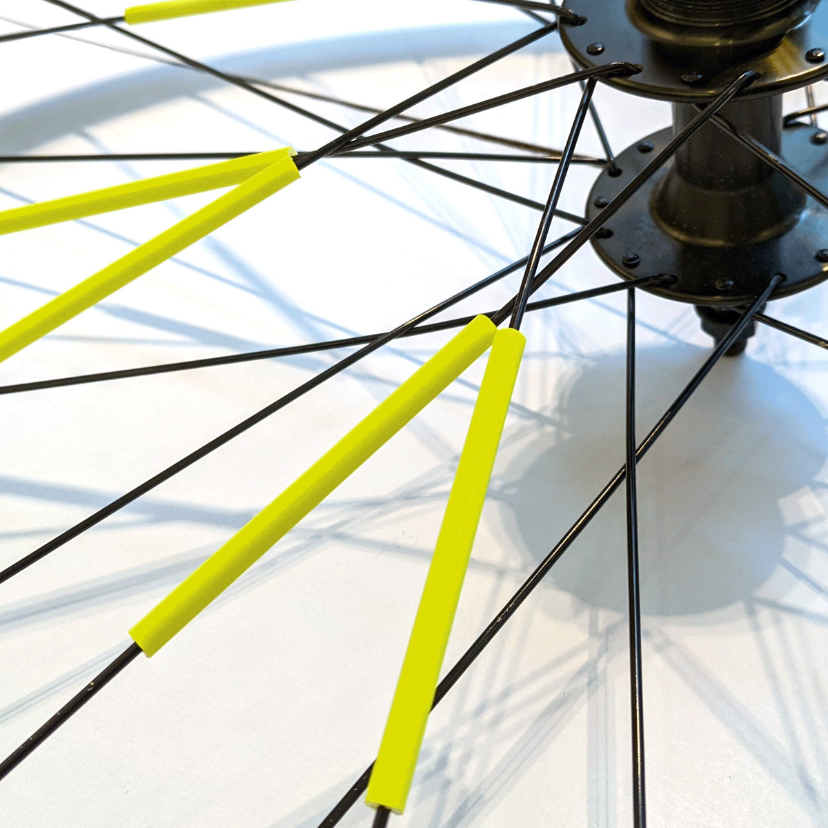 Rainette Speichenreflektoren in Neongelb an Fahrradfelge befestigt, schwarze Speichen mit gelben Reflektoren im Detail