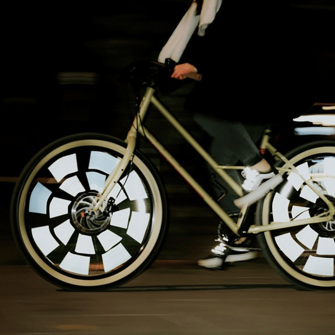 Fahrrad in Fahrt bei Nacht, die Rainette Speichenreflektoren an beiden Rädern leuchten weiß auf