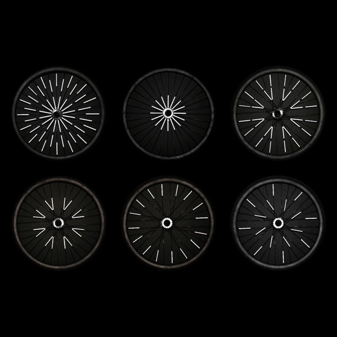 Sechs Fahrradräder bei Nacht mit unterschiedlich verteilten Rainette Speichenreflektoren, die weiß aufleuchten