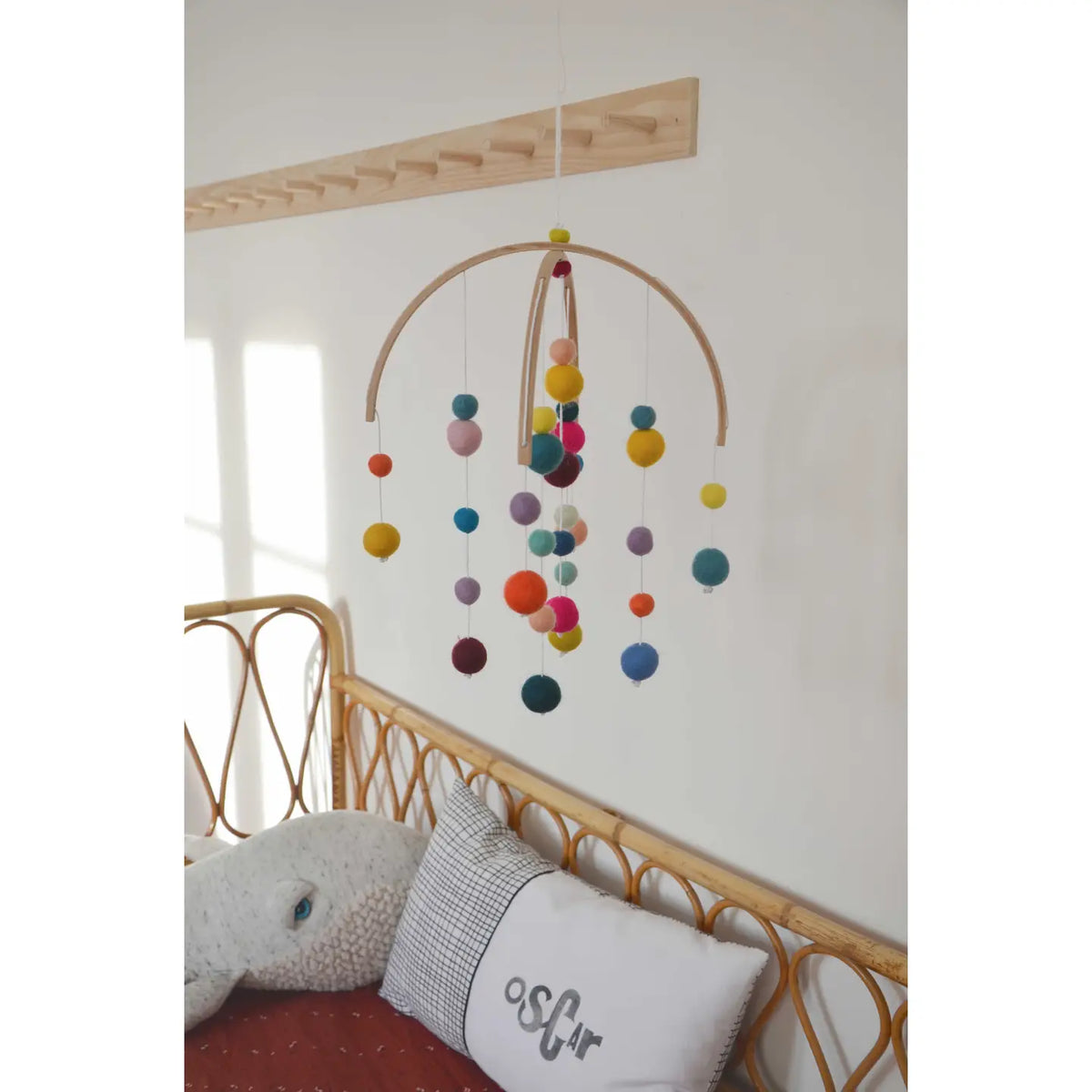 Buntes Filzkugel-Mobile von CALM for dreamers an der Zimmerdecke, darunter ein Rattanbett